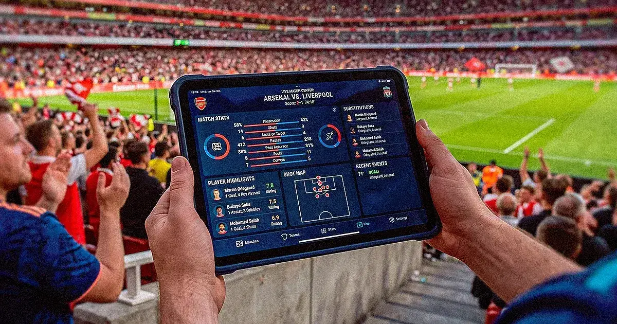 Aficionado sostiene una tableta con su alineación de fantasy futbol en el estadio