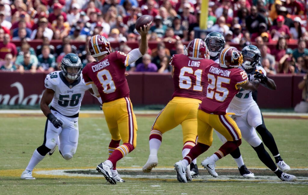 Quarterback de la NFL lanzando un pase protegido por su línea ofensiva