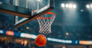 Balón de basquetbol cae junto al aro en una arena, guía de momios NBA