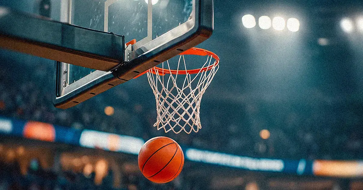 Balón de basquetbol cae junto al aro en una arena, guía de momios NBA